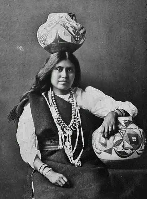 Portrait of a Pueblo woman, posing with traditional Pueblo pottery.